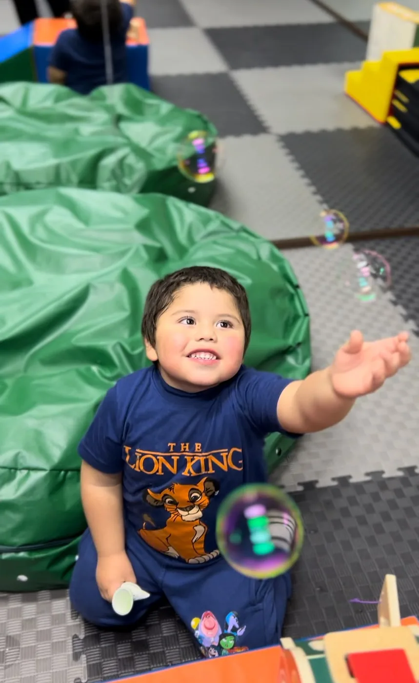 Niño participando en una actividad lúdica con burbujas en INFANCIACTIVA