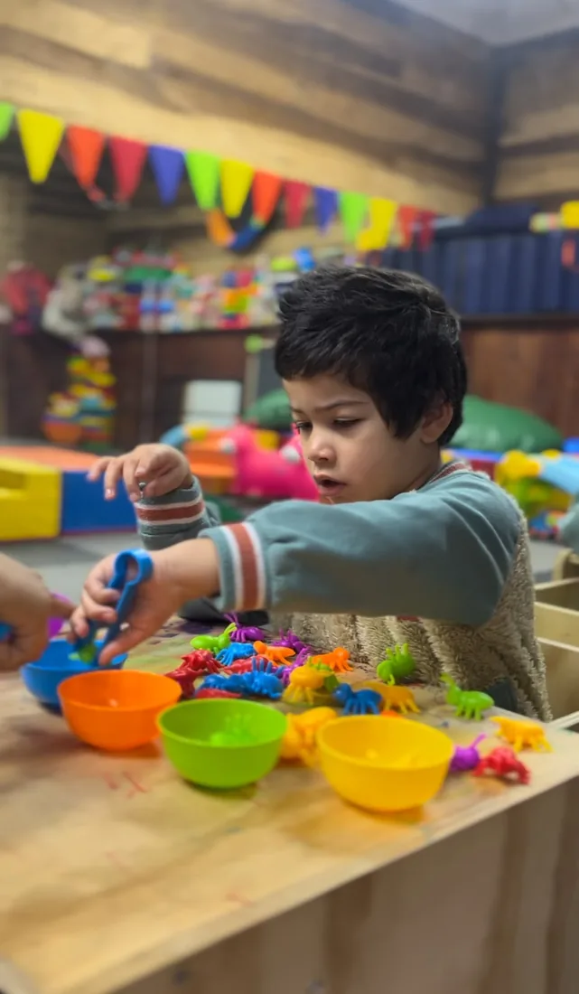 Niño explorando materiales de colores en INFANCIACTIVA